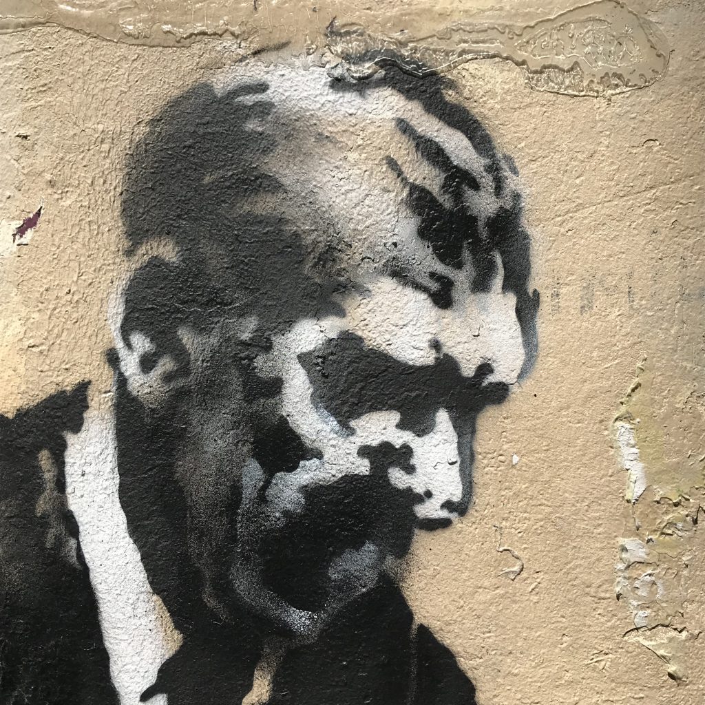 The face of Banksy’s Businessman with a Saw mural, emphasizing the interaction between the businessman and the dog near the Sorbonne University.