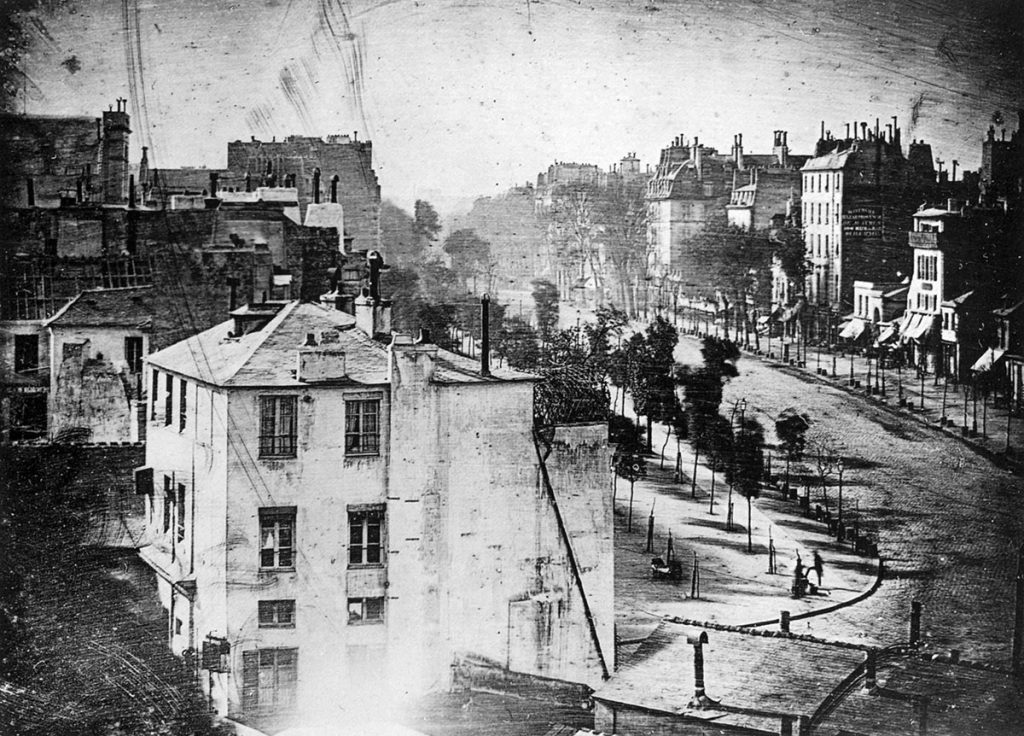 The first known photograph of a human, taken on Boulevard du Temple in 1838 by Louis Daguerre, shows a shoe shiner and his customer on an otherwise empty Parisian street.