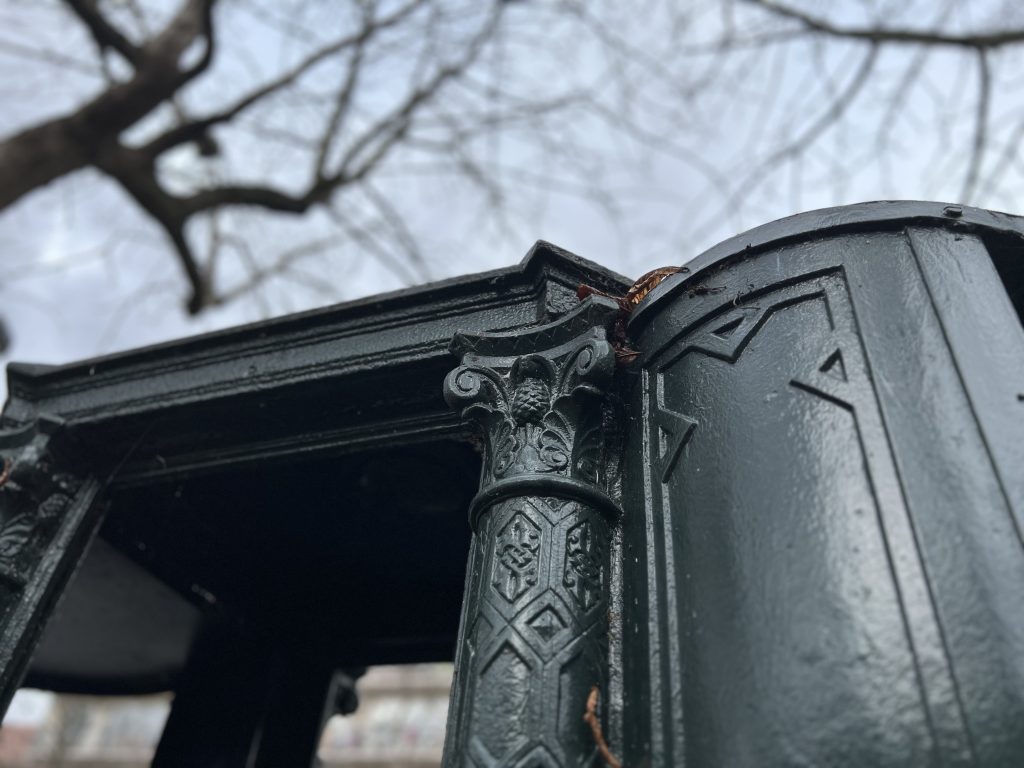 Close-up of cast iron decorations on the 19th-century pissoir at Boulevard Arago in Paris, showcasing detailed ornamental design.