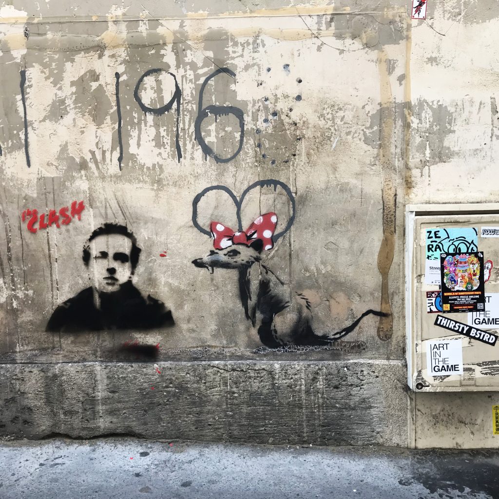 Banksy mural in Paris featuring a rat with a red polka-dot bow resembling Minnie Mouse, painted on a wall near Rue de Clignancourt.