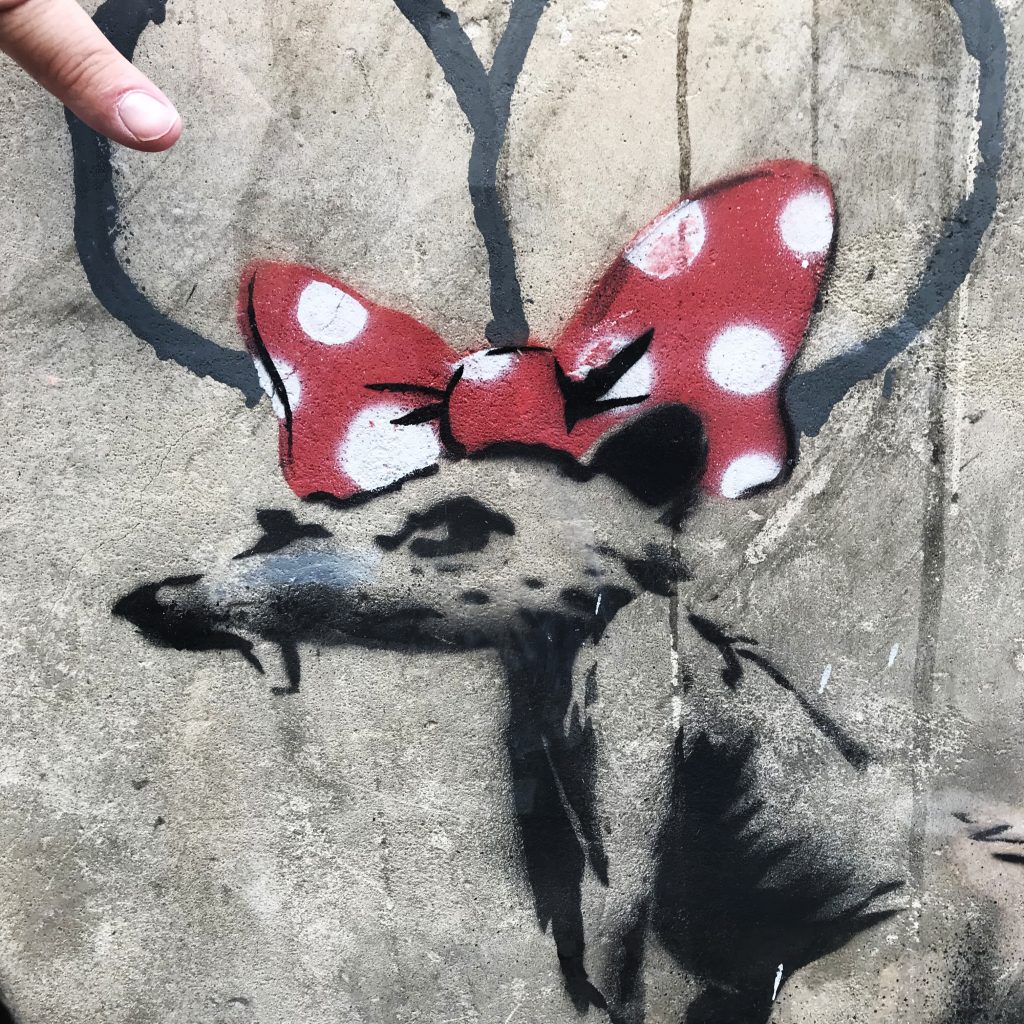 Detailed view of Banksy’s Businessman with a Saw mural, highlighting the three-legged dog and the bone offered by the businessman near the Sorbonne.