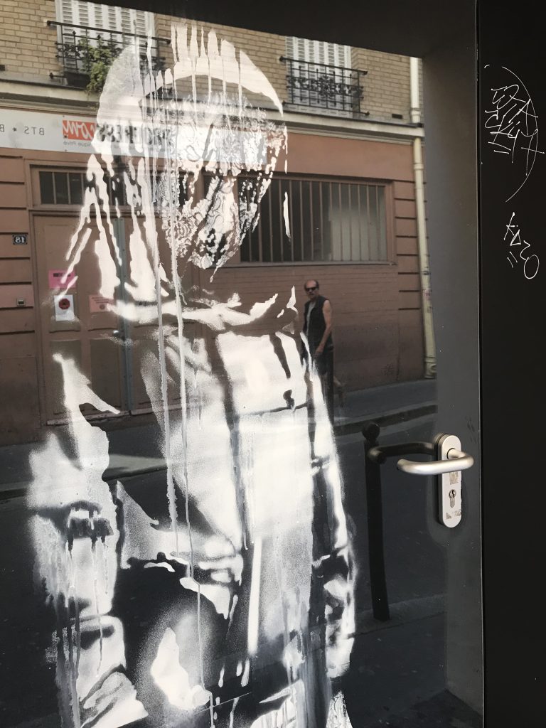 Close-up of Banksy’s The Mourning Figure mural, focusing on the veiled head and delicate stenciling details outside the Bataclan.