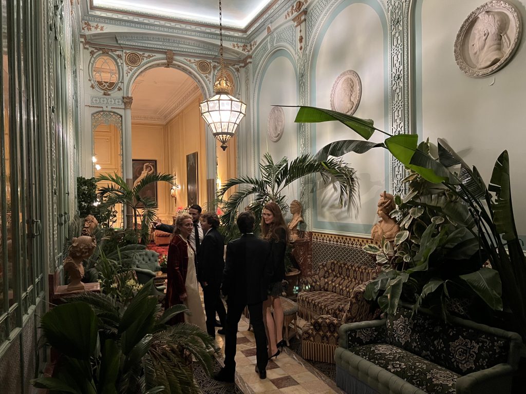 People socializing in the Winter Garden at the Travellers Club in Paris, showcasing vintage décor and a unique historical ambiance.