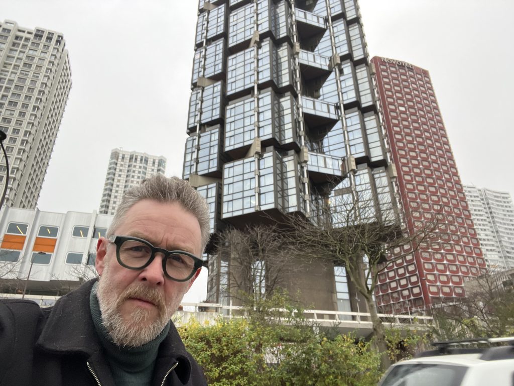 Portrait of the author in front of the modernist towers at Front de Seine, showcasing the unique architectural backdrop.